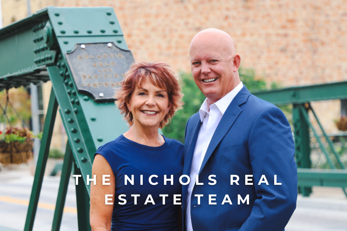 Arroyo Grande Real Estate Photo of Scoot & Sandy Nichols of The Nichols Real Estate Team with the "Swinging Bridge" located in the Village of Arroyo Grande in the background. Your local experts in the Arroyo Grande Real Estate Market.