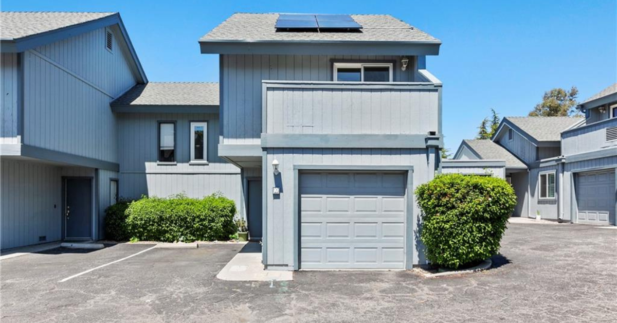 Exterior view of the recently sold townhouse at 10 Quail Ridge, featuring modern gray siding, a one-car garage, solar panels, and a well-maintained community setting.